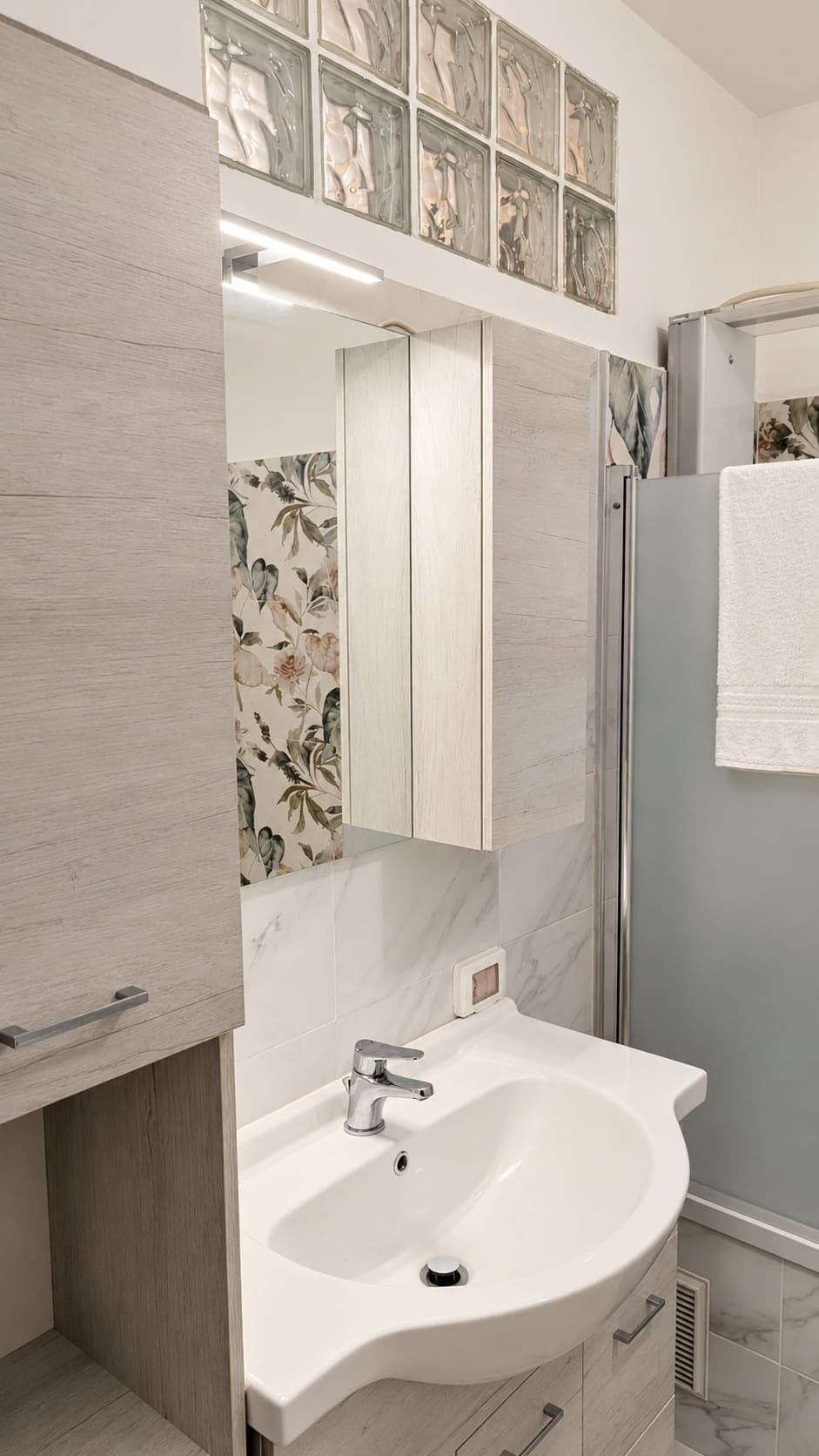 Lavabo con mobile, specchio e piastrelle decorate a fiori