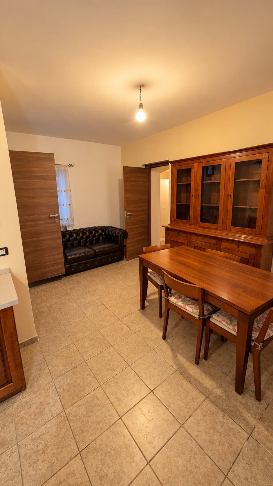 Zona giorno con tavolo da pranzo in legno, credenza e divano in pelle